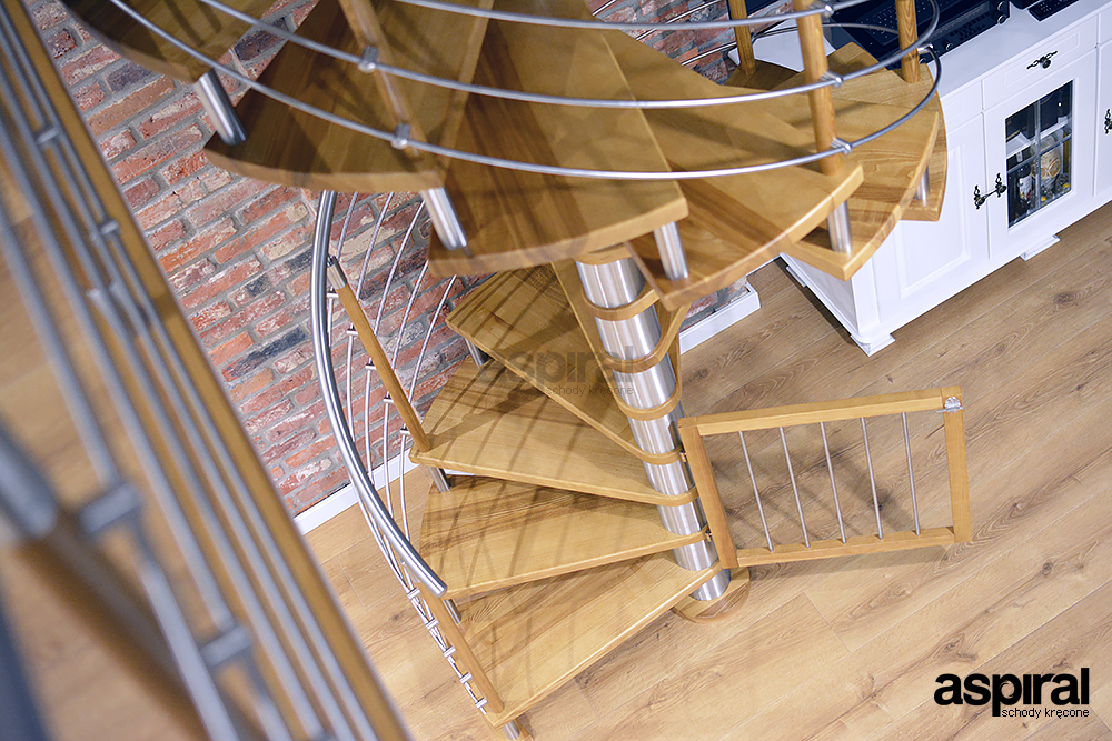 Drewniane schody spiralne z metalową balustradą. Drzwiczki chroniące przed wejściem dziecka na schod...