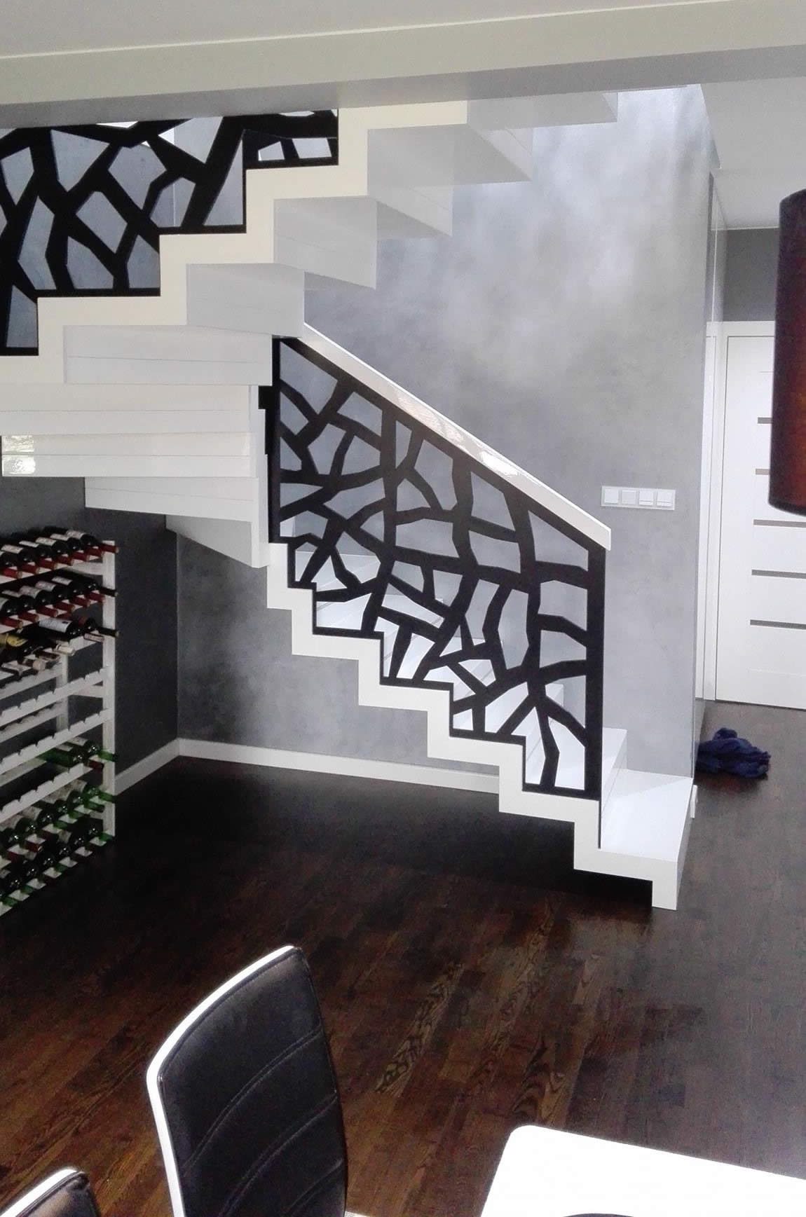 Zabiegowe schody dywanowe malowane na biało w kontraście z czarną balustradą ażurową.  Realizacja fi...