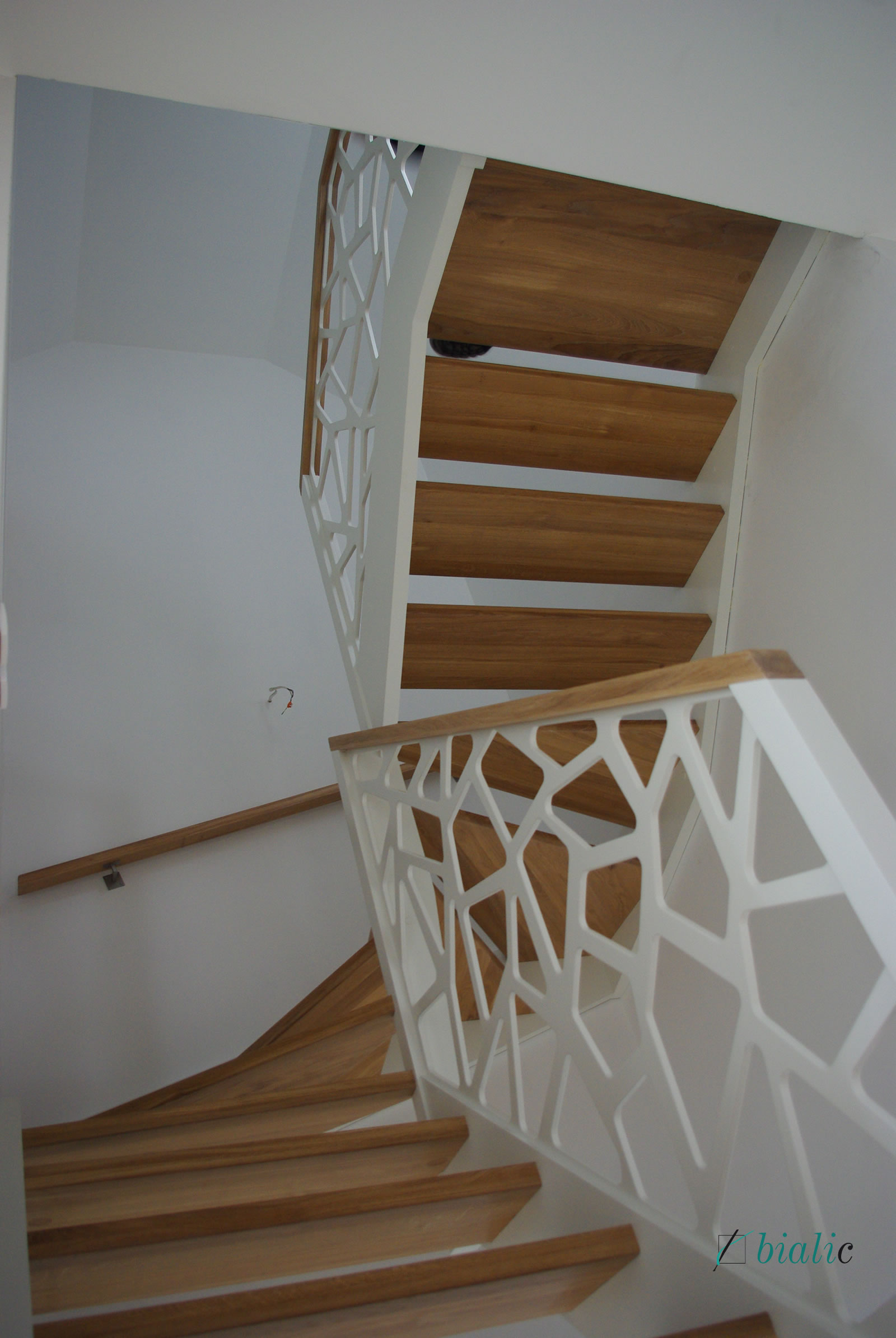 Klasyczne schody z białymi policzkami - wypełnienie ażurowe pod poręczami także w kolorze białym. Re...